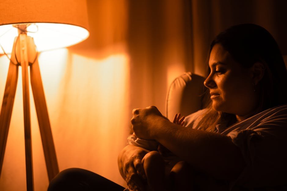 A mother tenderly cradling her infant in soft, warm lamp light.