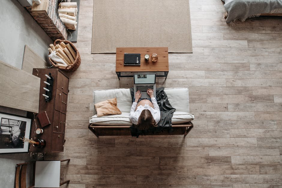 Pregnant woman working from home in a cozy living room environment with a laptop on a wooden floor.