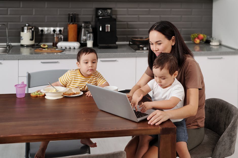 A mother with her two sons uses a laptop in the kitchen during breakfast time.