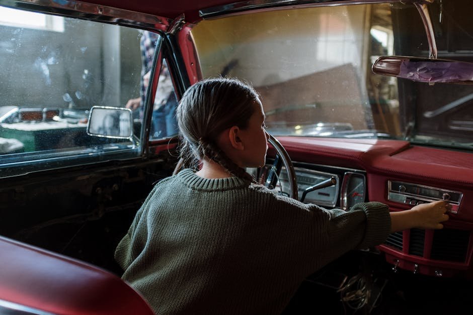 Young girl inside vintage car, fascinated by dashboard and controls.