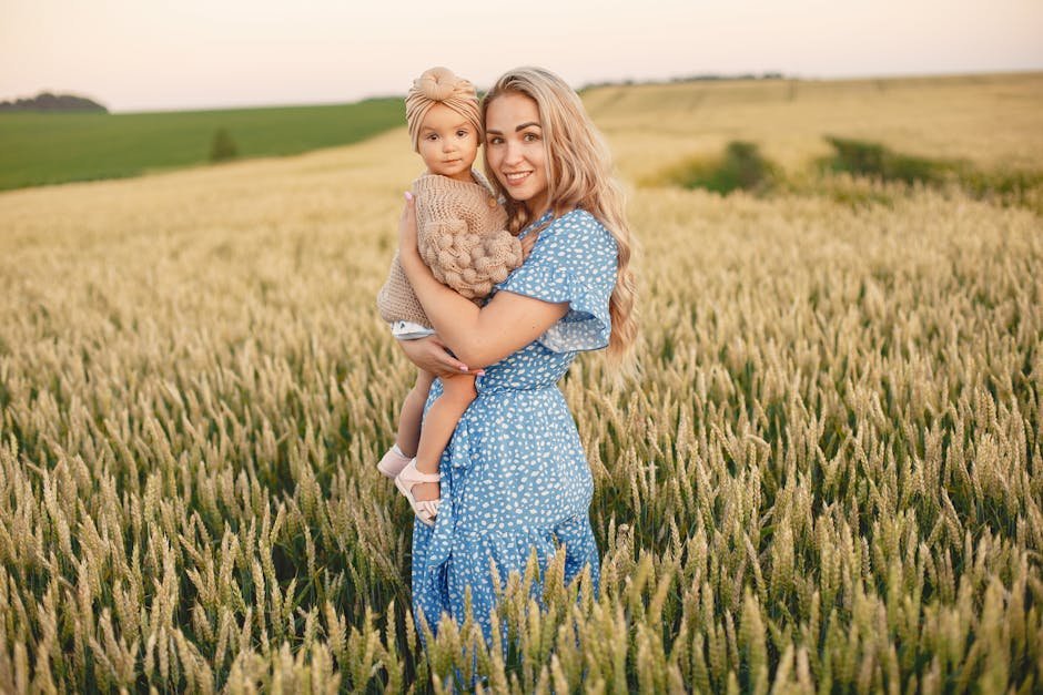 A joyful mother holding her child in a lush wheat field during sunset, embracing nature.