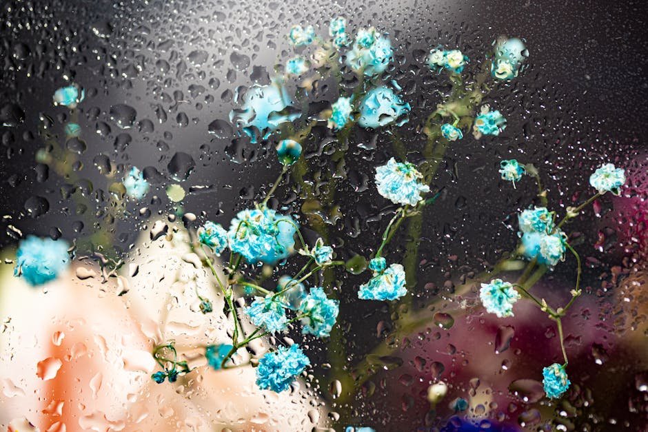 A mesmerizing display of blue flowers viewed through glass adorned with water droplets, creating a surreal visual effect.