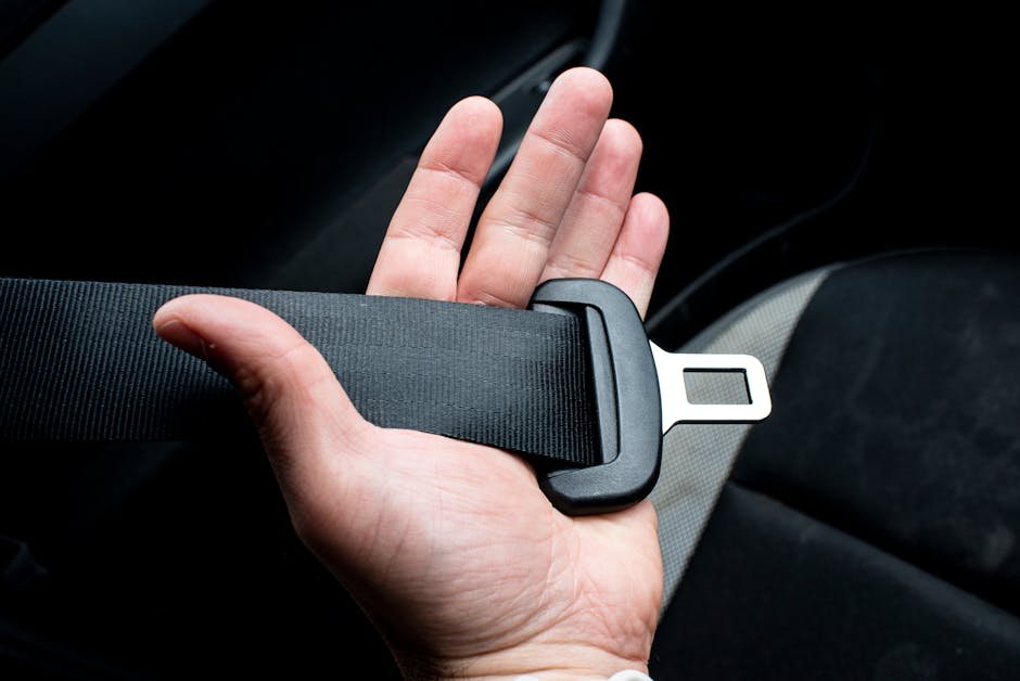 Close-up of a hand holding a car seat belt for safety and security.