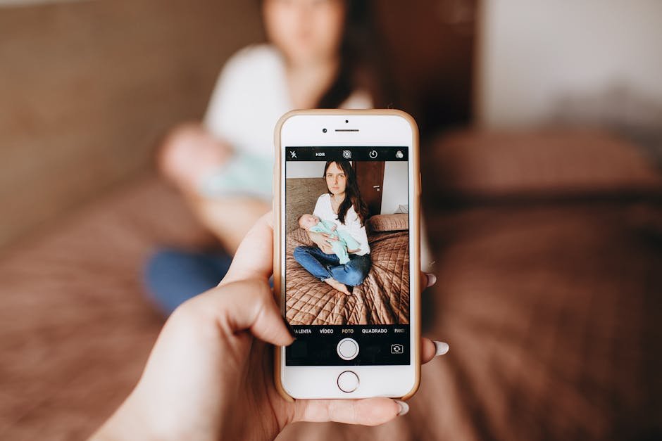 A woman sitting with her baby, captured through a smartphone camera indoors.