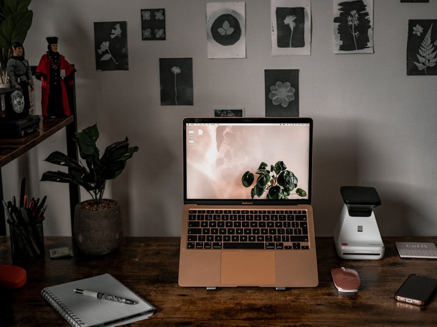 A stylish desk setup with laptop, plants, and wall art, ideal for remote work and creativity.